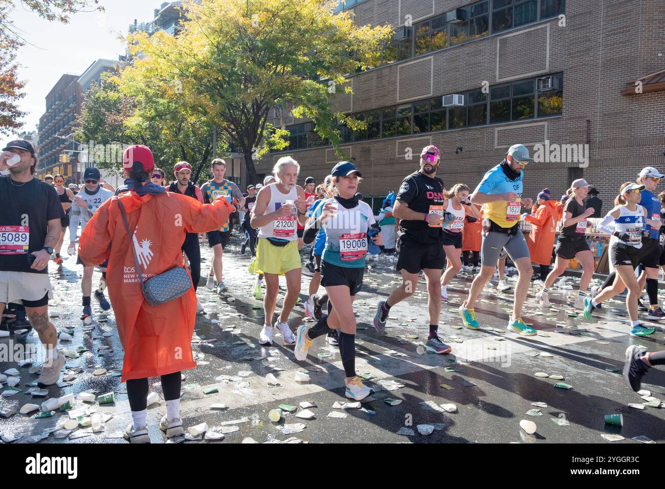 Ai 16 km della maratona di New York del 2024, i volontari mantengono i corridori idratati con bicchieri d'acqua. Su Bedford Avenue a Williamsburg, Brooklyn, N. Foto Stock