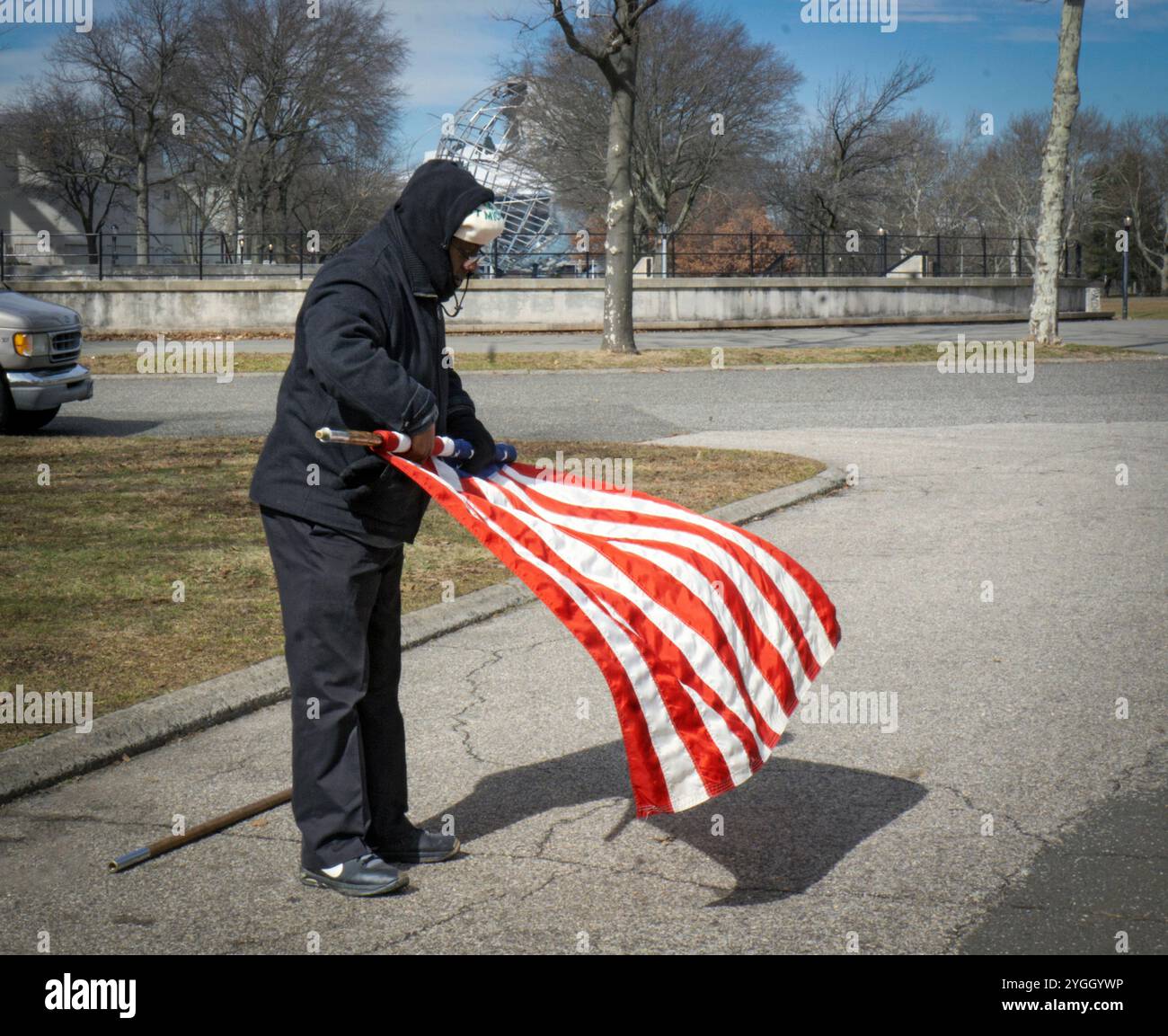 Dopo un servizio di preghiera cattolica all'aperto, un adoratore fa rotolare la bandiera americana. In un parco nel Queens, New York City, vicino a un monumento al Vatican Pavilion. Foto Stock