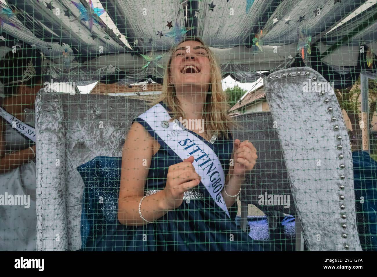 Inghilterra, Kent, Whitstable, Whitstable Carnival, Miss Sittingbourne Beauty Queen seduto dietro lo schermo a rete protettiva Carnival Float Foto Stock