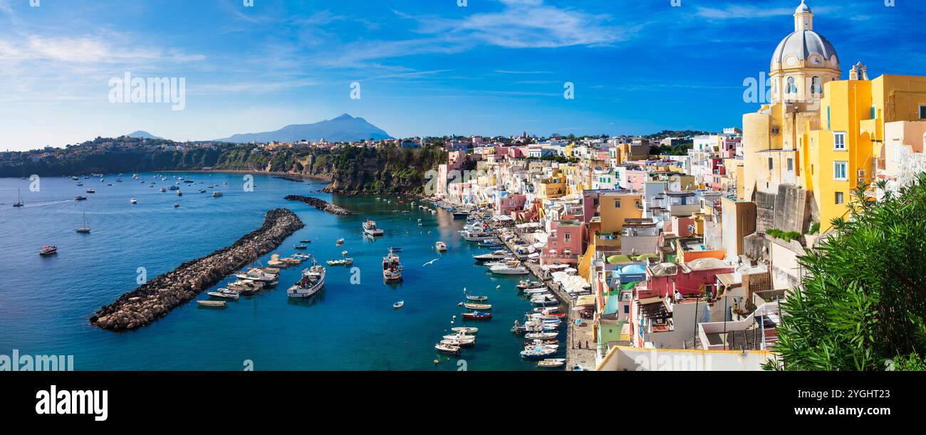 Viaggi in Italia e luoghi di interesse. L'isola più pittoresca e colorata - la bellissima Procida nel golfo di Napoli. Vista panoramica del porto di Corricella con chiesa gialla Foto Stock