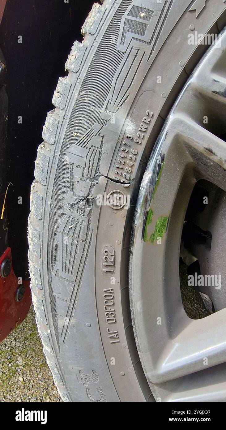 la parete laterale di uno pneumatico dell'auto e il cerchione sono danneggiati a causa di un incidente Foto Stock