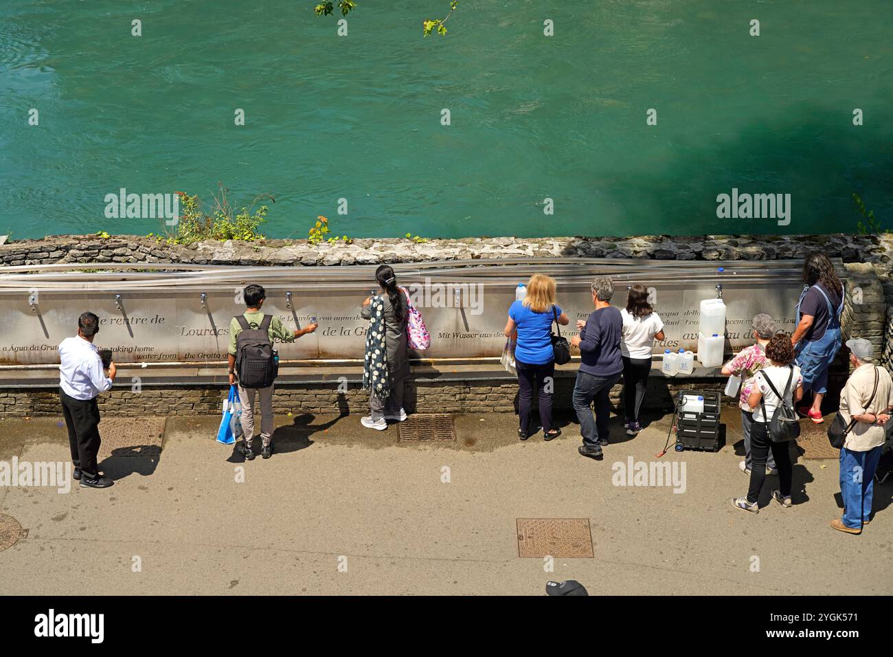 Pellegrini alla fontana con l'acqua Santa della sorgente del sito di pellegrinaggio mariano di Lourdes, Pirenei, Francia, Europa Foto Stock