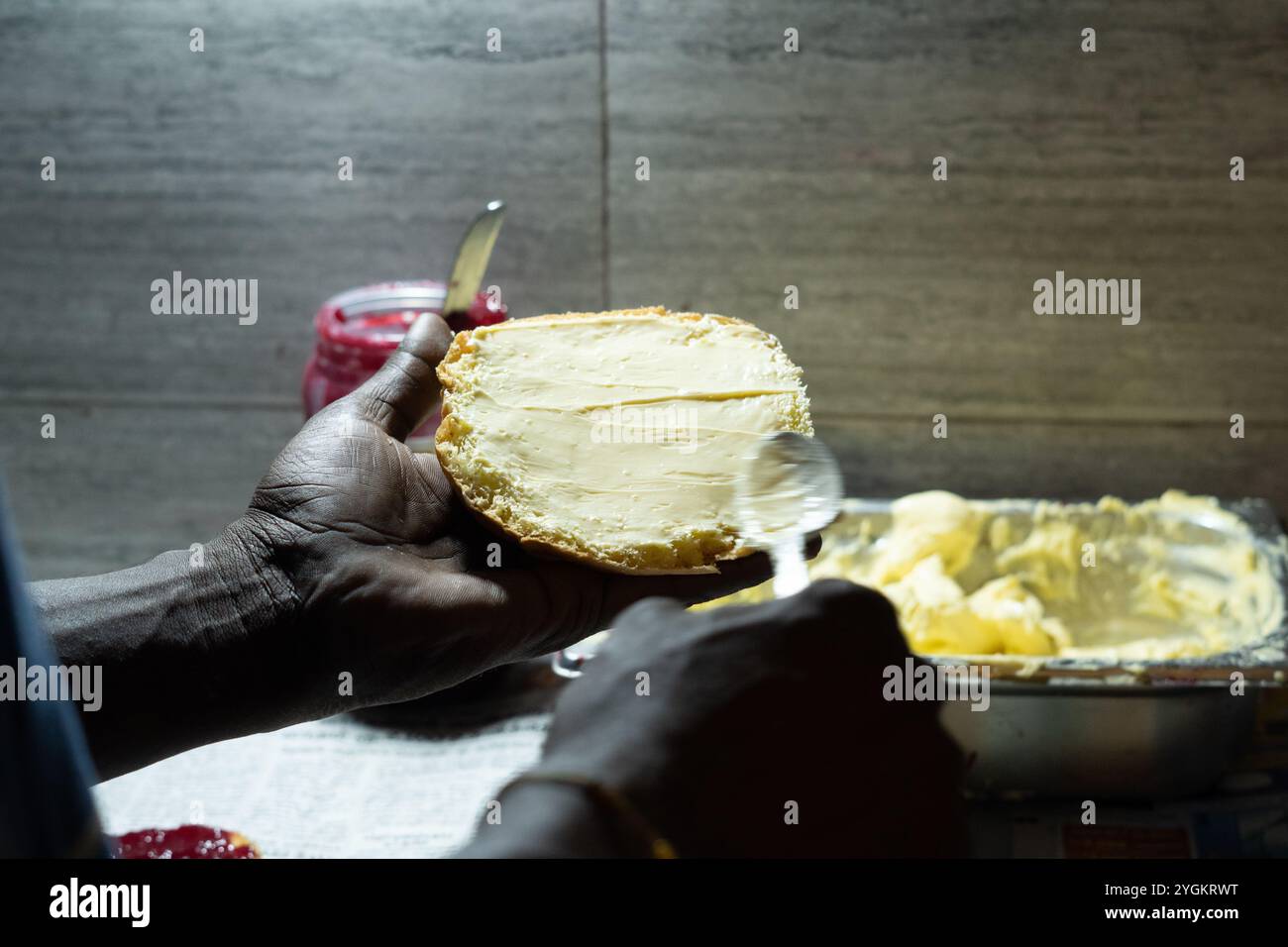 Uomo che aggiunge burro al panino Foto Stock