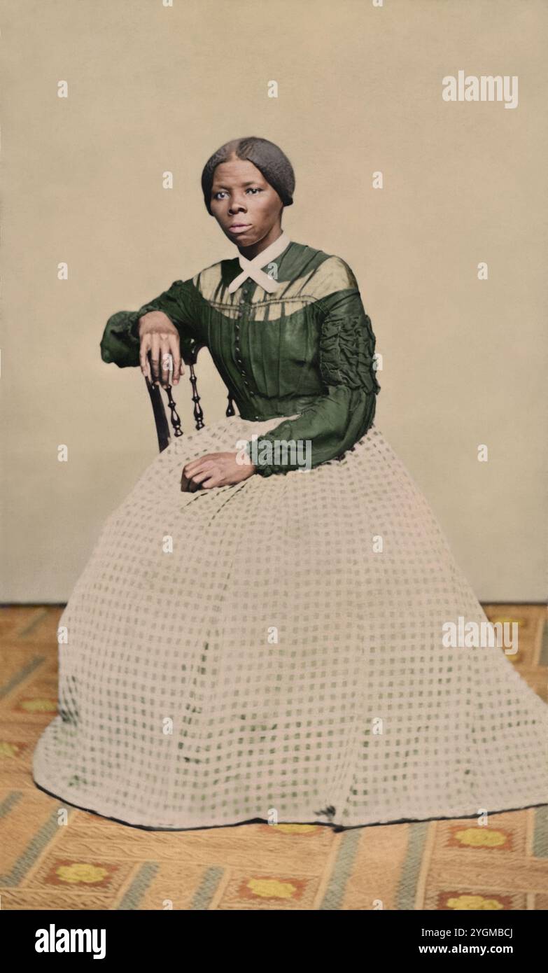 Una carta-de-visite di Harriet Tubman (circa 46-47) nel 1868-69. E' seduta, girata verso sinistra. Una mano poggia sul retro di una sedia di legno, un'altra sulle sue ginocchia. Creato da Benjamin Powelson, 77 Genesee St., Auburn, New York. Harriet Tubman seduto in una stanza interna. È posizionata leggermente girata a destra e guarda fuori dalla telecamera. La sua mano destra poggia sul retro di una sedia di legno e la sua mano sinistra è in grembo. Un tappeto dai motivi audaci copre il pavimento e la parete o la goccia dietro di lei è di colore chiaro vuoto. Tubman indossa un corpetto nero (mi sono preso la libertà di aggiungere col Foto Stock