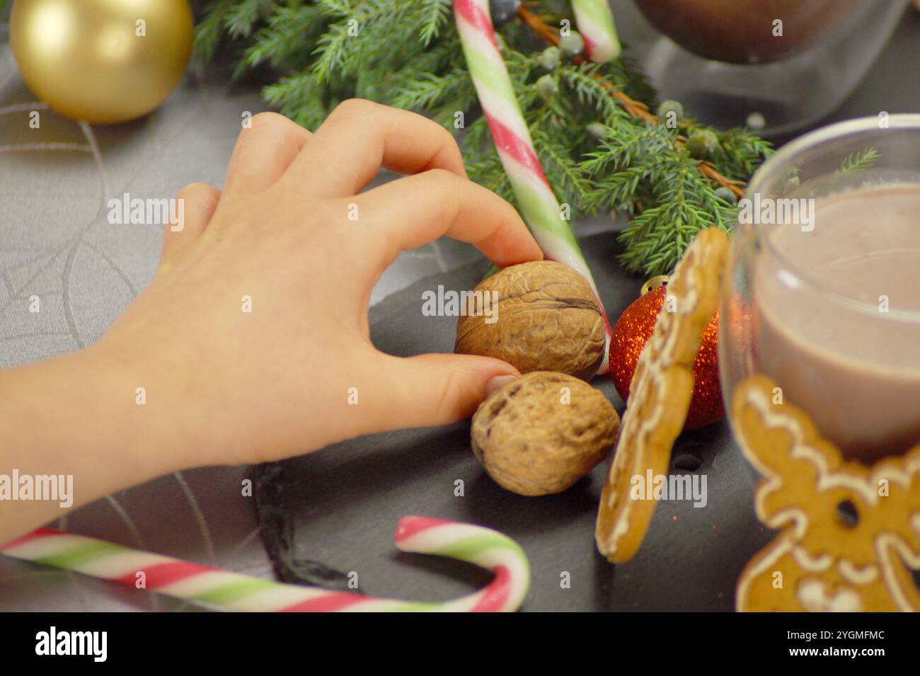 Anno nuovo, preparazione natalizia. Il bambino assembla con le proprie mani un set di bastoncini di caramelle, palle dell'albero di Natale, biscotti al pan di zenzero nella forma di o Foto Stock