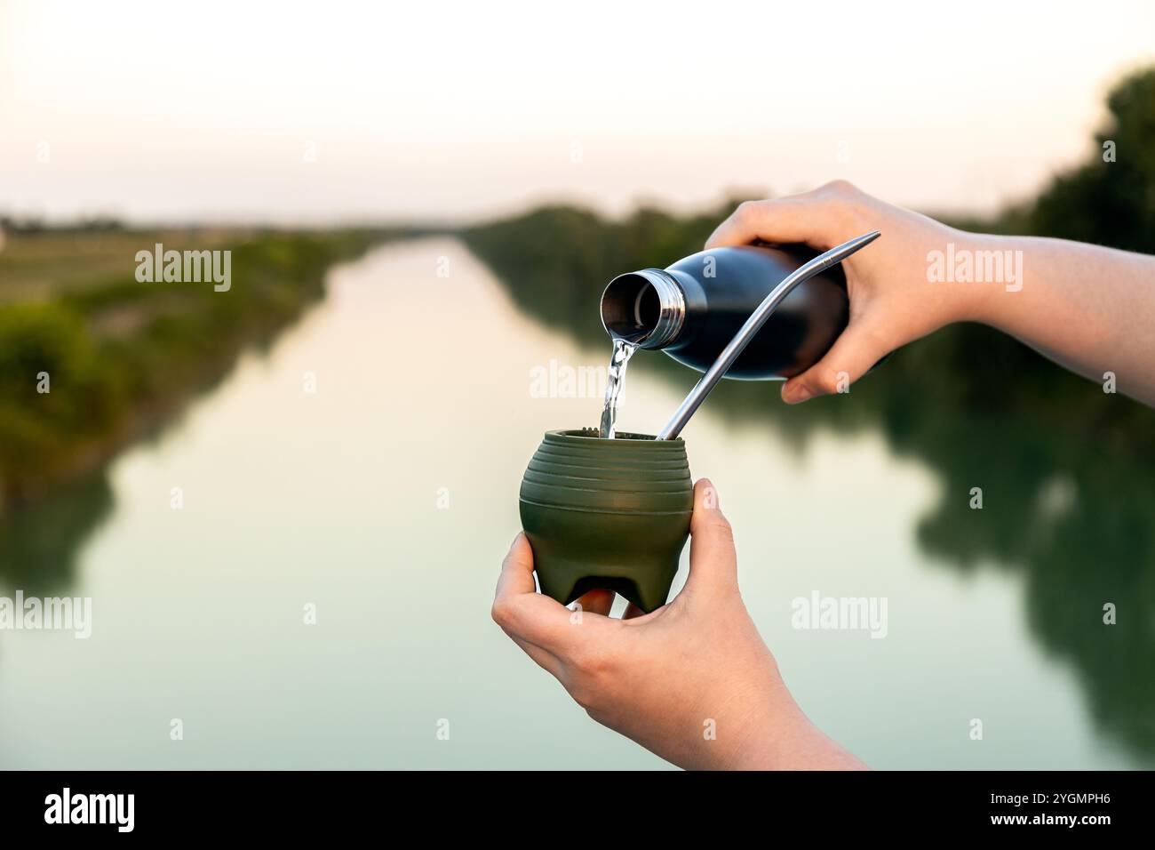 Versare acqua calda in una bustina di silicone Mate con una cannuccia metallica per yerba Mate (chimarrão) all'aperto Foto Stock