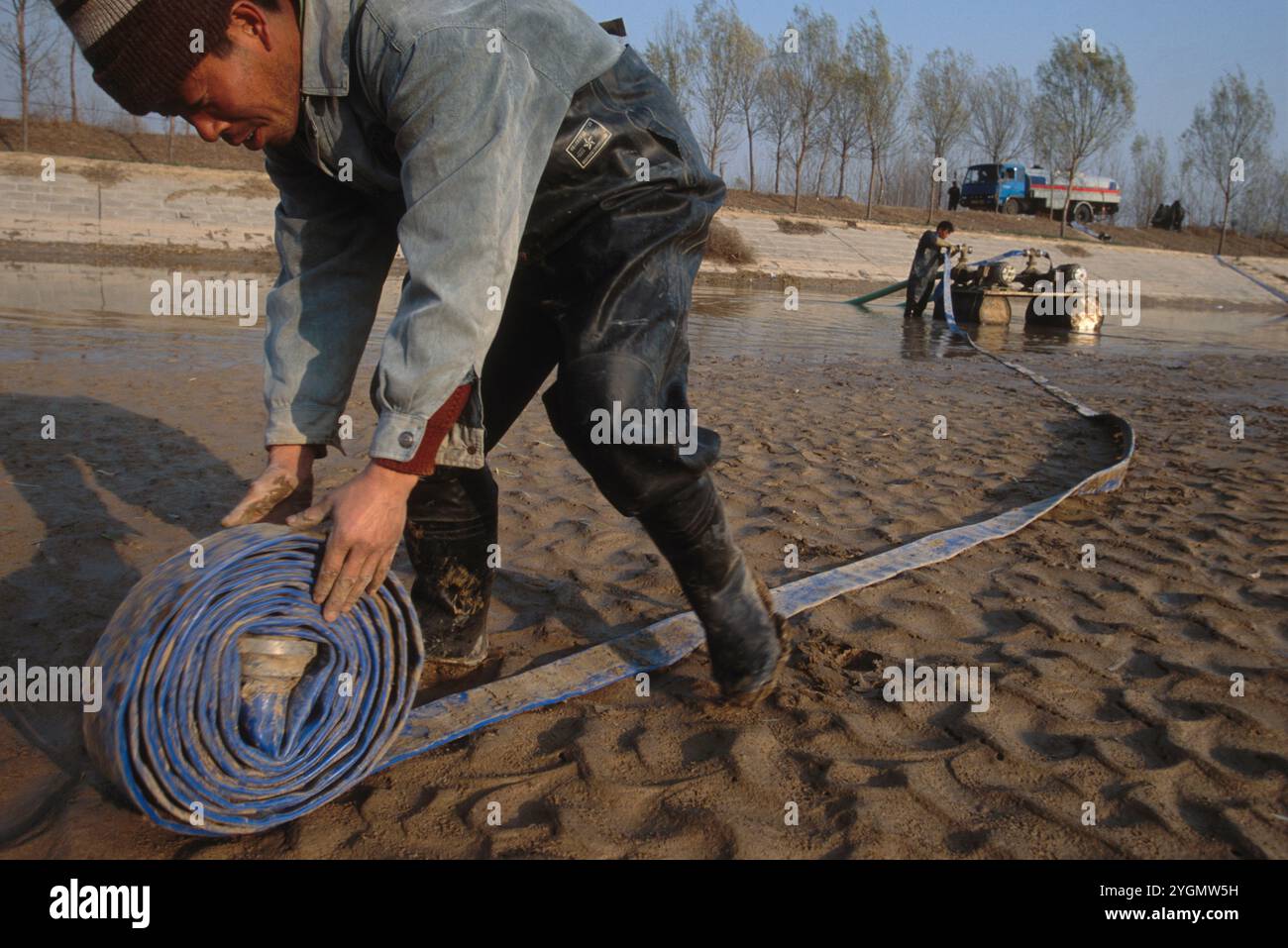 Lavoratori che preparano una draga e attrezzature per tubi flessibili per sgombrare un canale di deviazione dell'irrigazione vicino a Ji'nan, in Cina, che è ostruito da limo. Il canale deve essere sgombrato ogni anno come Yello Foto Stock