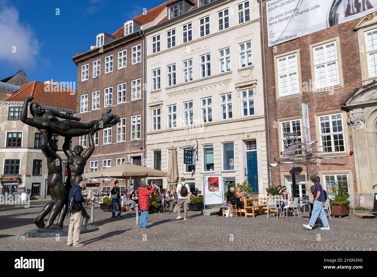 Persone che gusteranno cibo e caffè in un caffè in piazza Gammel Strand con una scultura in bronzo di Svend Wiig Hansen nella piazza Foto Stock