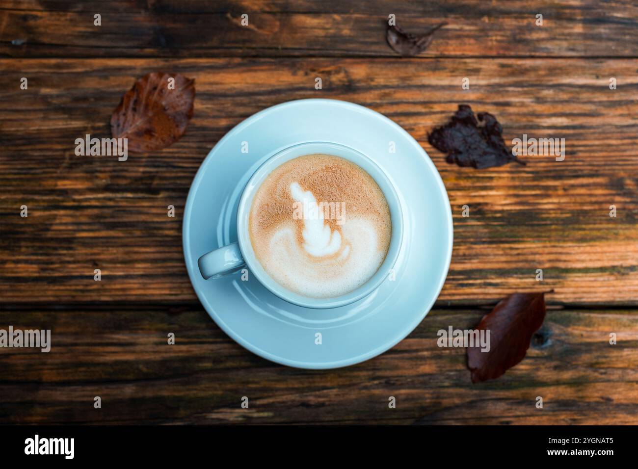 Una tazza di caffè su un tavolo di legno e foglie d'autunno marroni. Vista dall'alto, disposizione piatta. Foto Stock