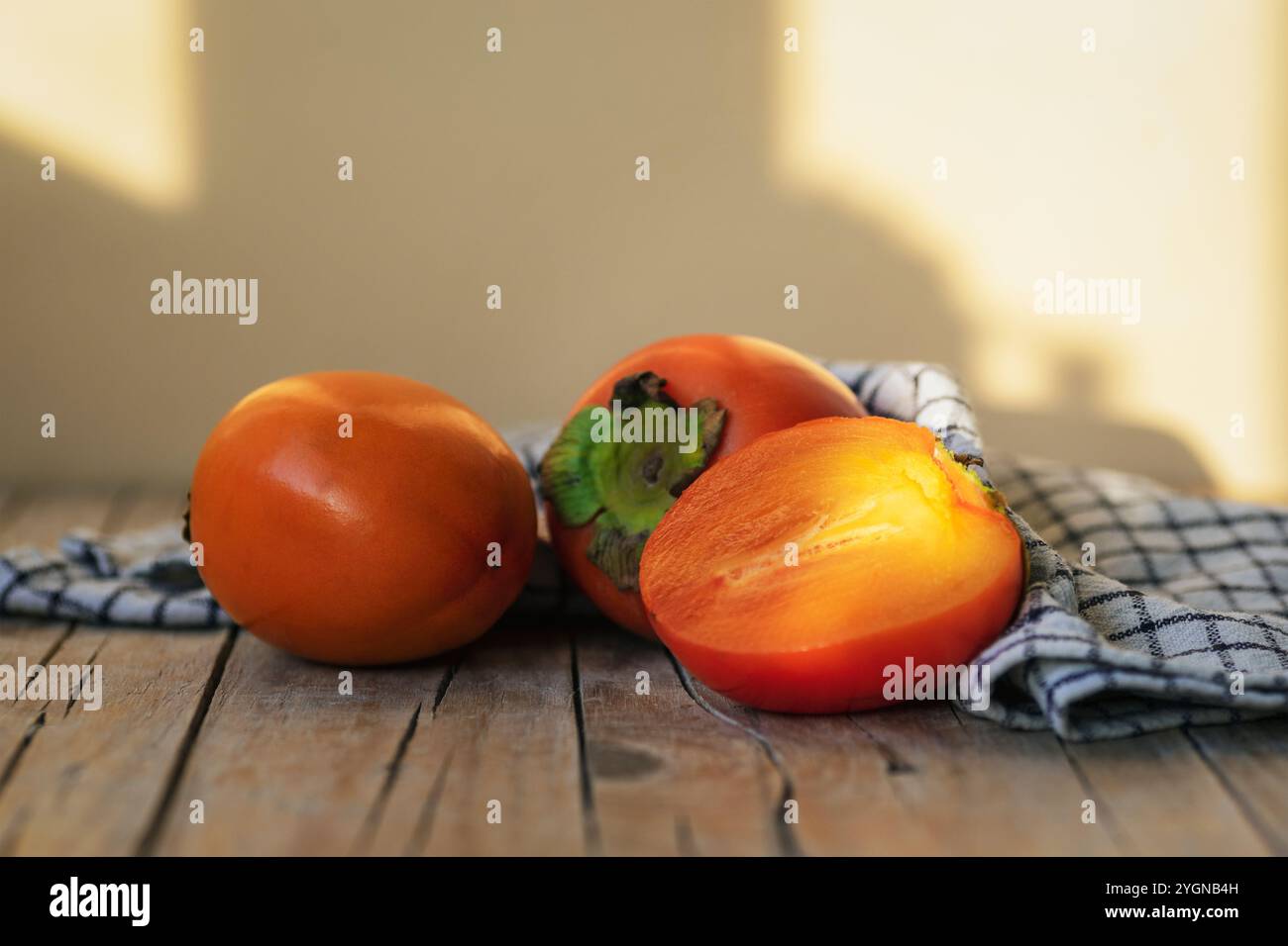 Frutta fresca matura di cachi su tavola in legno alla luce del sole. Primo piano. Foto Stock