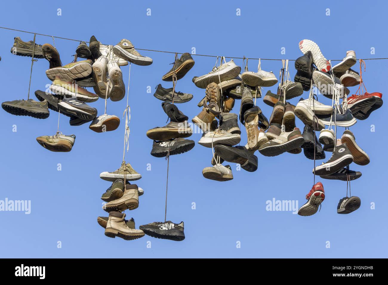 Scarpe, stivali, scarpe da ginnastica, ... appesi a una corda in aria sopra la Grapengiesserstrasse, città medievale di Lueneburg, città anseatica di Lueneburg, L Foto Stock