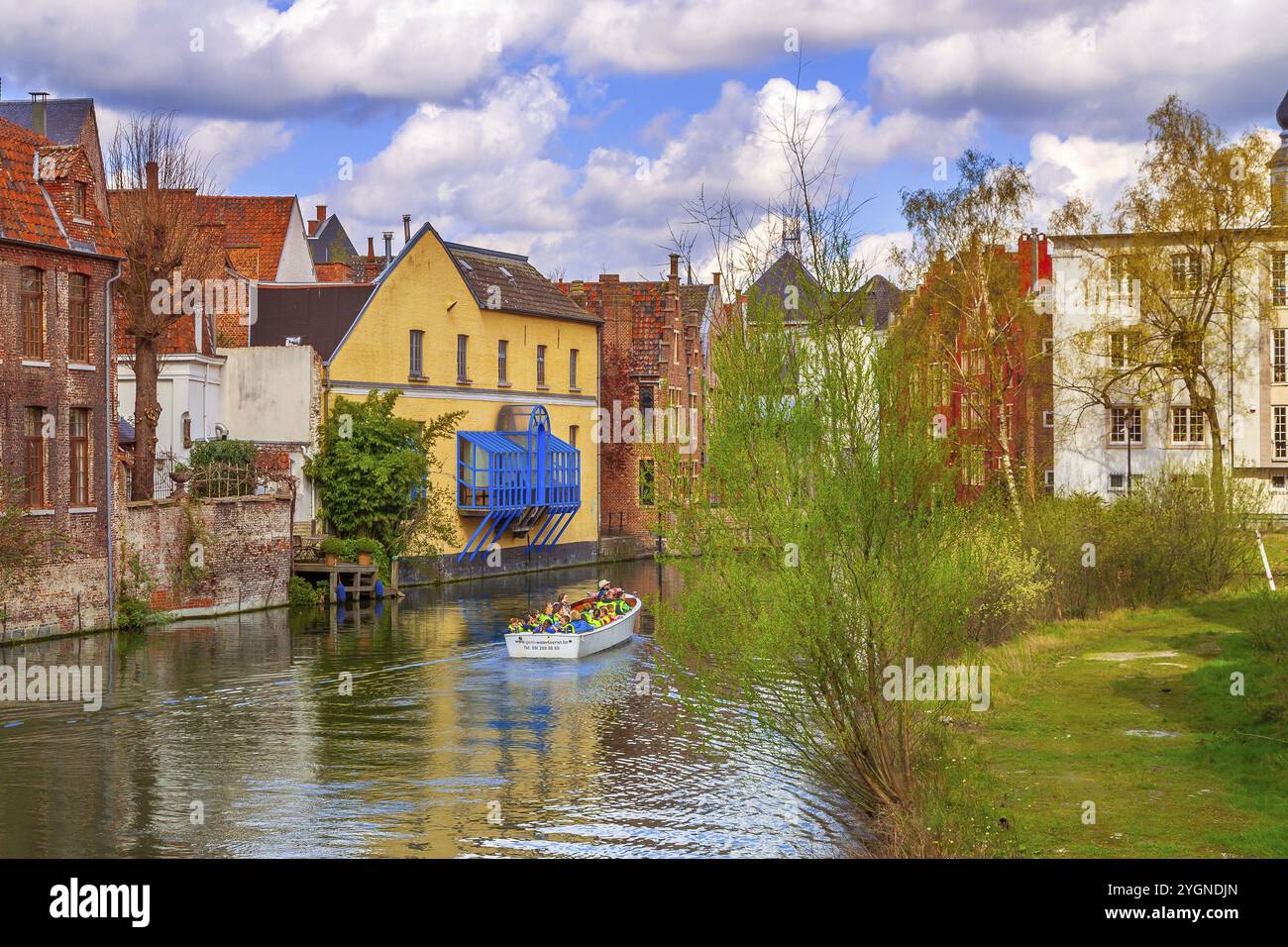 Gand, Belgio, 12 aprile 2016: Vecchie case lungo il canale e la barca con turisti nella popolare destinazione turistica Gent, Europa Foto Stock