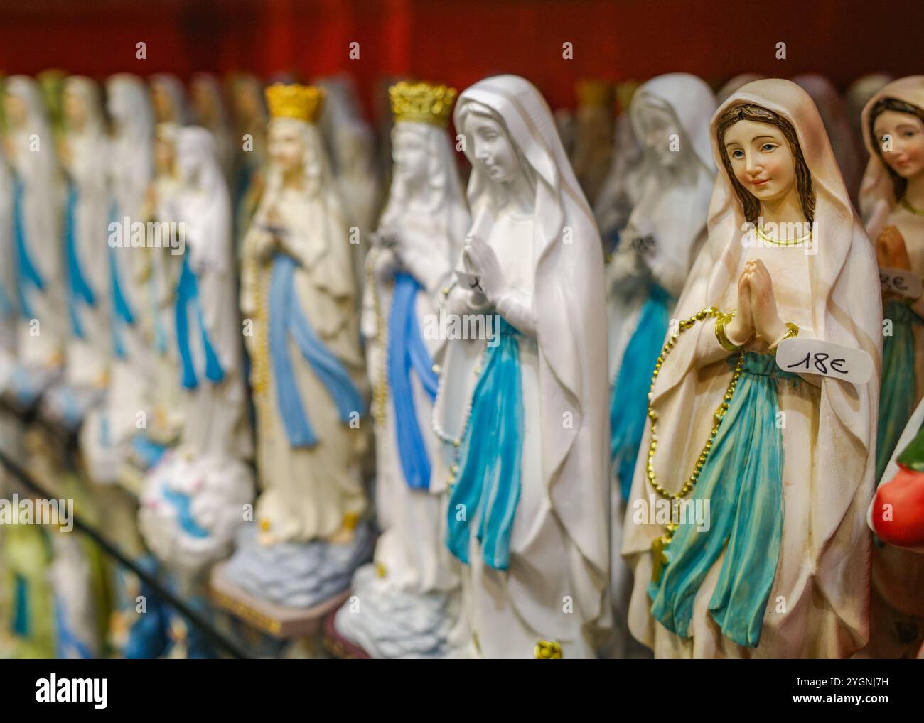 Lourdes, Francia - 1 novembre 2024: Statue della Vergine Maria, candele e altri cimeli cattolici in vendita in un negozio di articoli da regalo a Lourdes Foto Stock