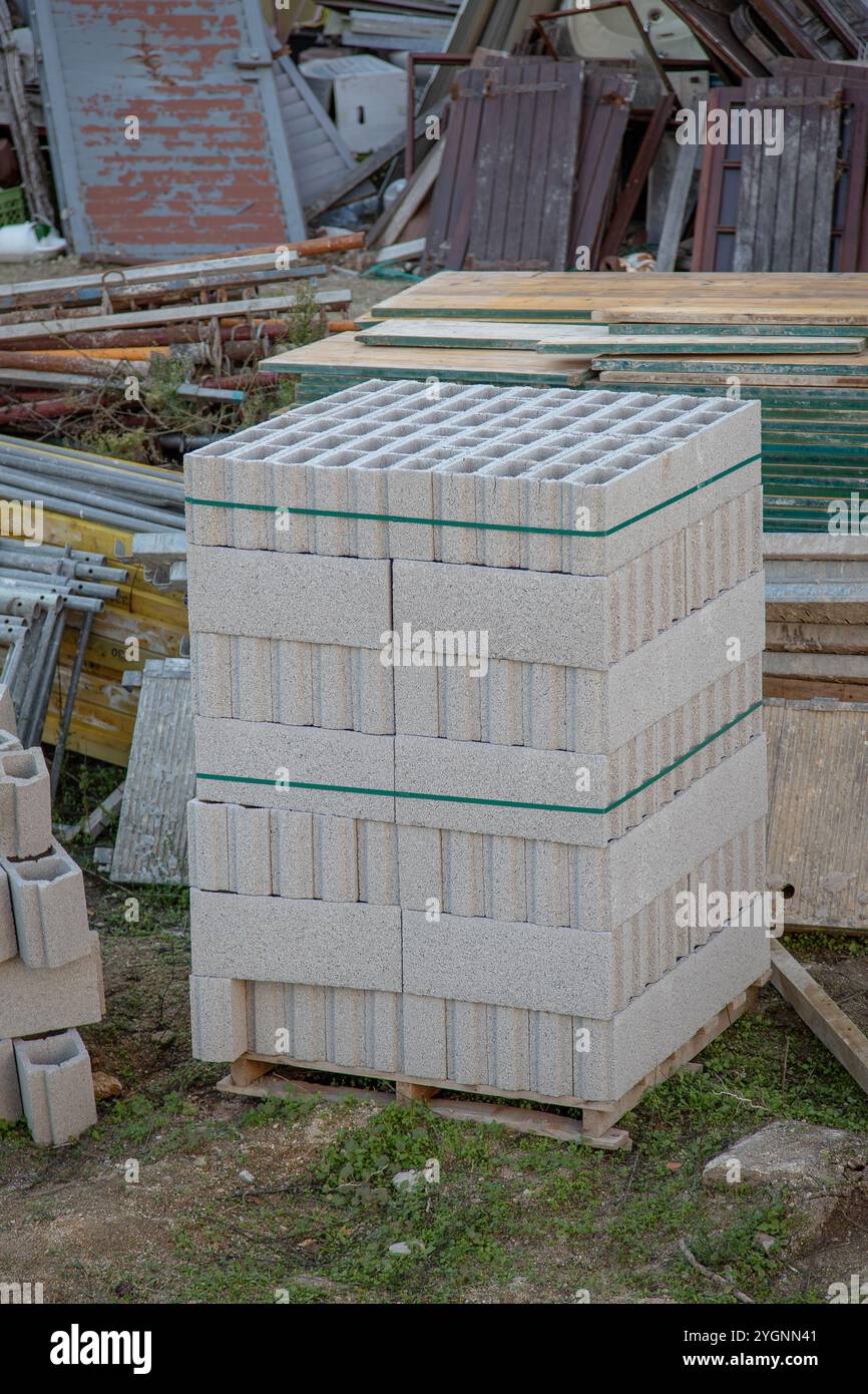 Pallet impilato in modo ordinato di blocchi di calcestruzzo grigio con centri cavi, pronto per l'uso nelle costruzioni Foto Stock