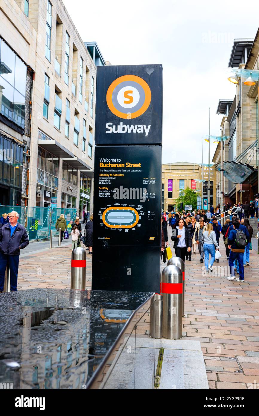 Un cartello di spicco situato fuori dalla stazione della metropolitana di Buchanan Street, Glasgow, Scozia. Sullo sfondo, gli edifici fiancheggiano la strada, con pedoni Foto Stock