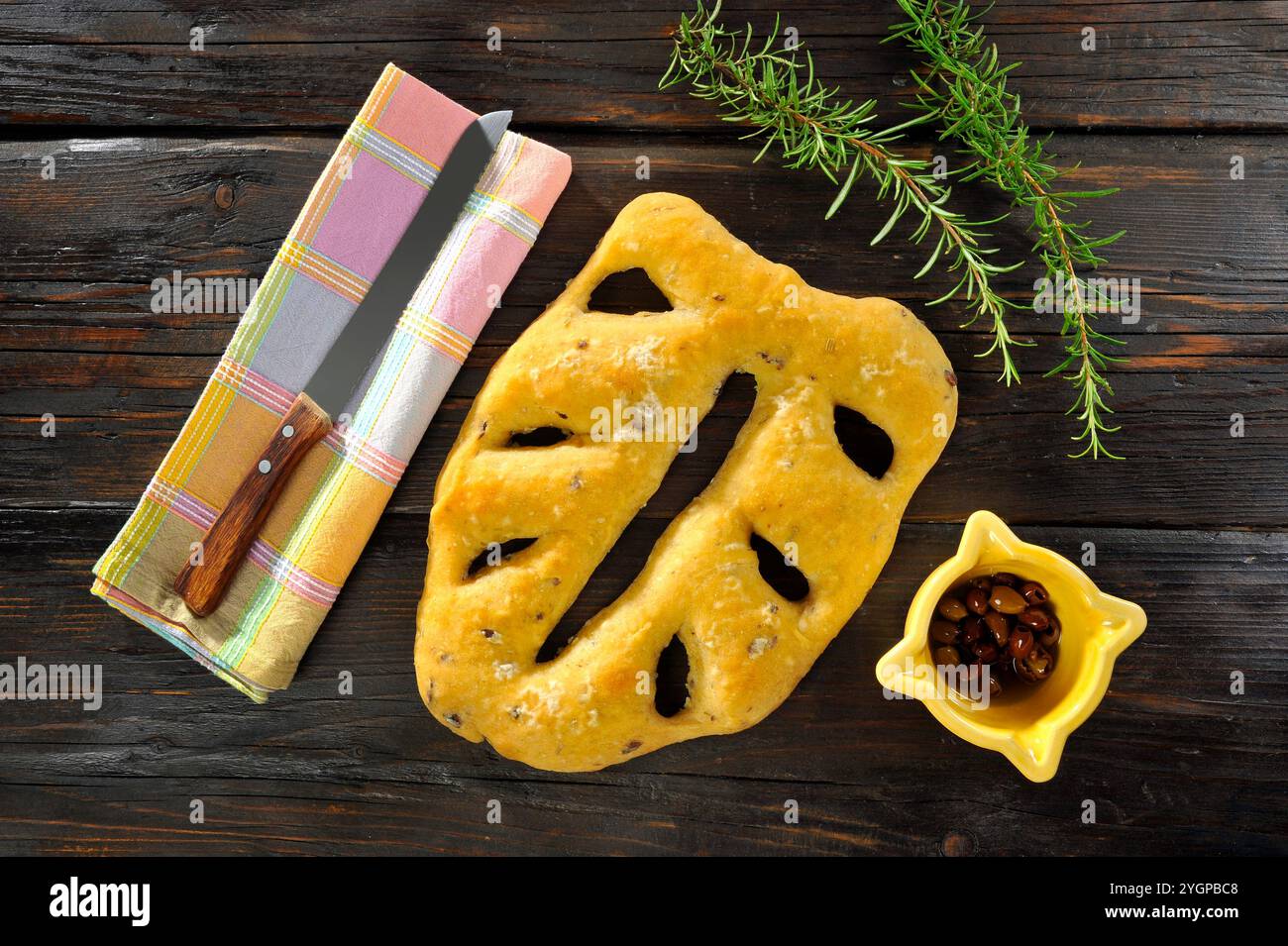 Focaccia a foglia su un tavolo in legno nero, con olive e rosmarino Foto Stock