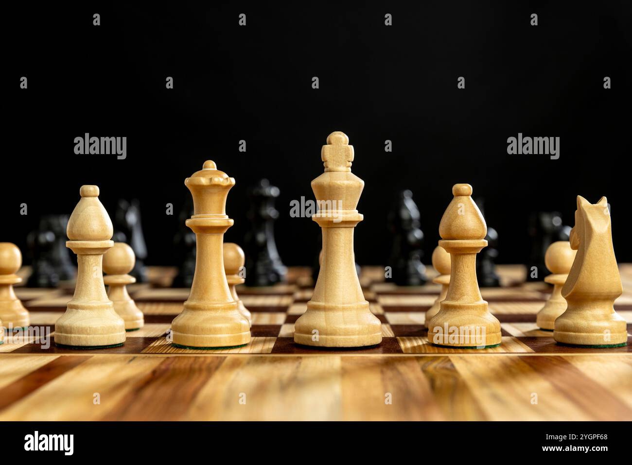 Scacchi di legno su scacchiera su sfondo nero Foto Stock