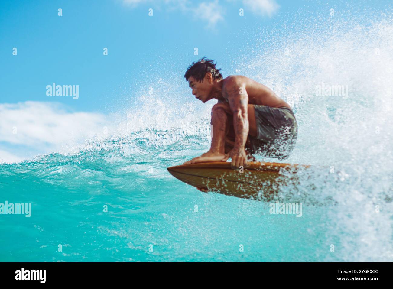 Arthur 'Toots' Anchinges cavalca un'onda al Queens di Waikiki sotto un cielo limpido Foto Stock