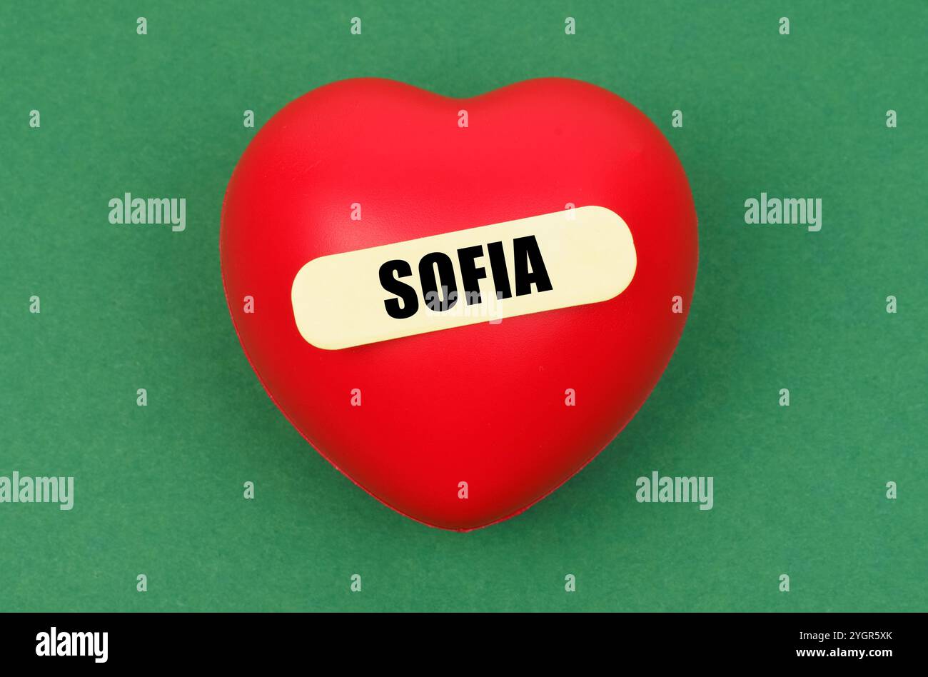Un sorprendente cuore rosso è esposto in modo prominente, con il nome Sofia, che trasmette un messaggio personale di amore su un vivido sfondo verde. Foto Stock