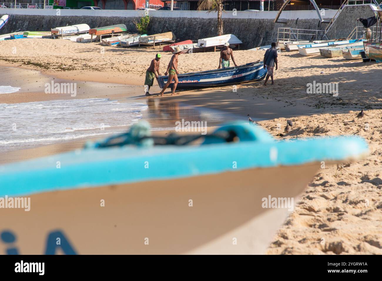 Si vedono pescatori che spingono una barca da pesca in mare sulla spiaggia di Rio Vermelho. Salvador, Bahia. Foto Stock