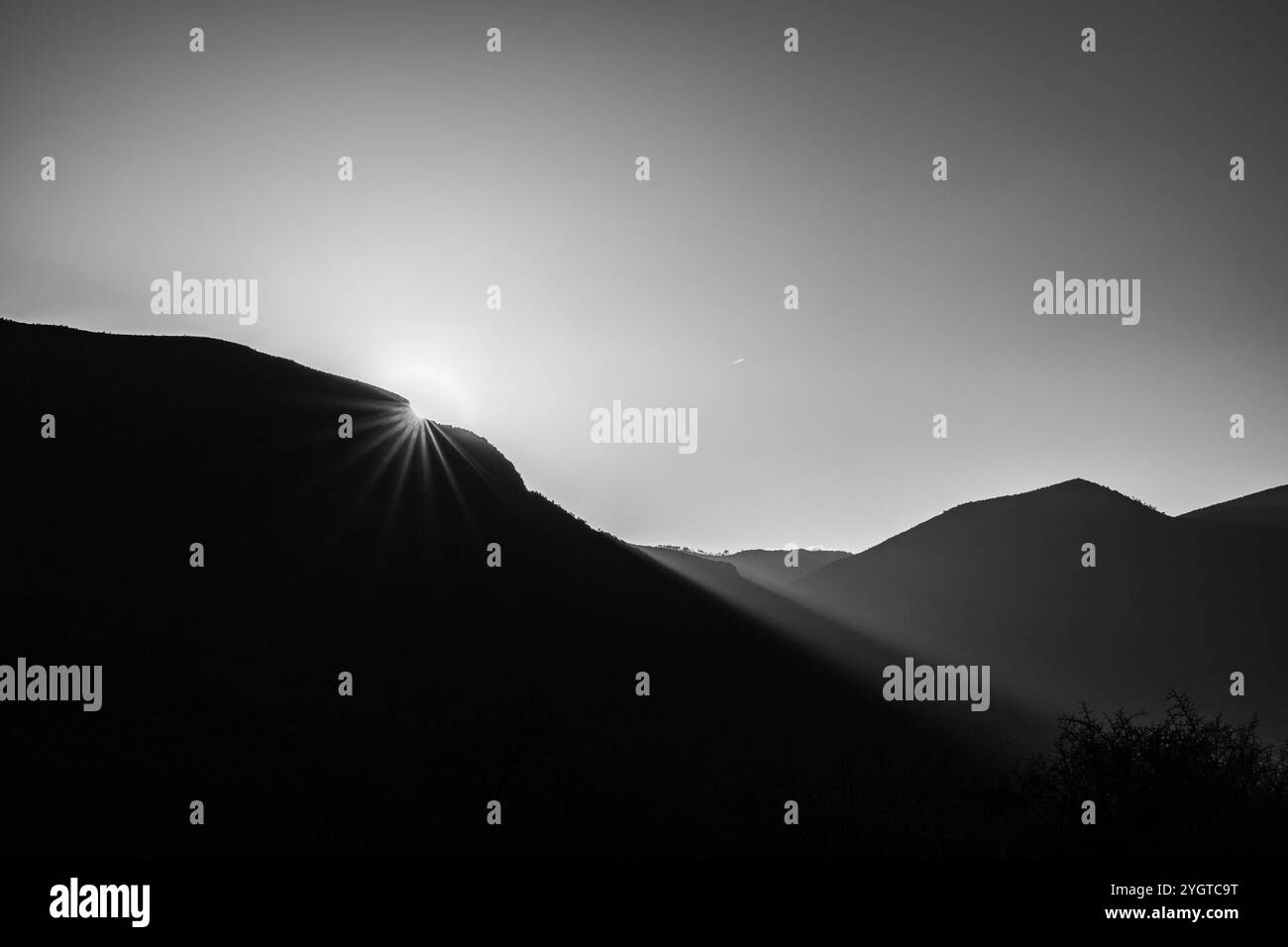 Profilo delle montagne al tramonto con il sole che si immerge dietro le montagne. Foto Stock