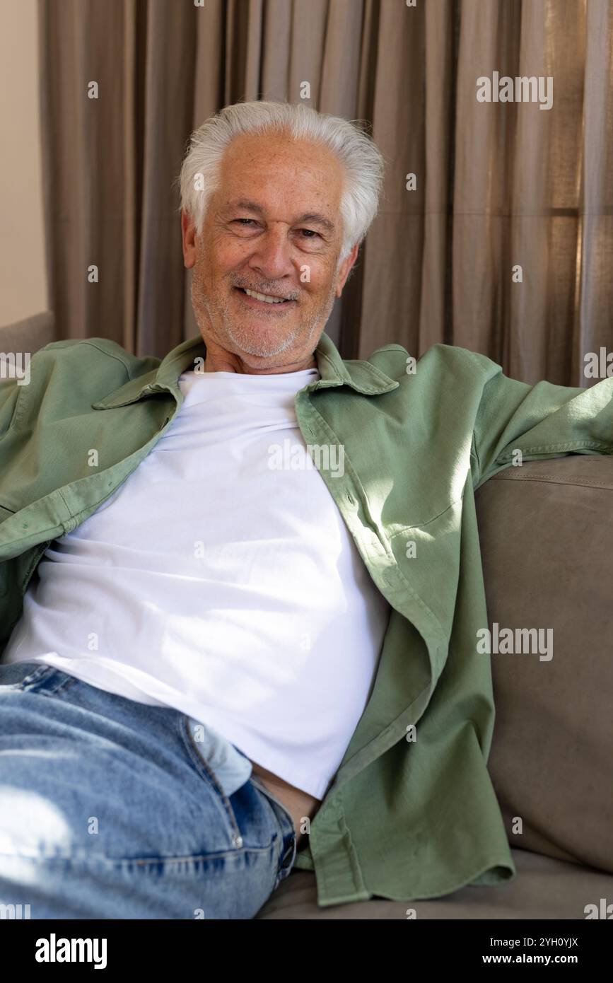 Rilassatevi a casa, un anziano sorridente seduto comodamente sul divano Foto Stock