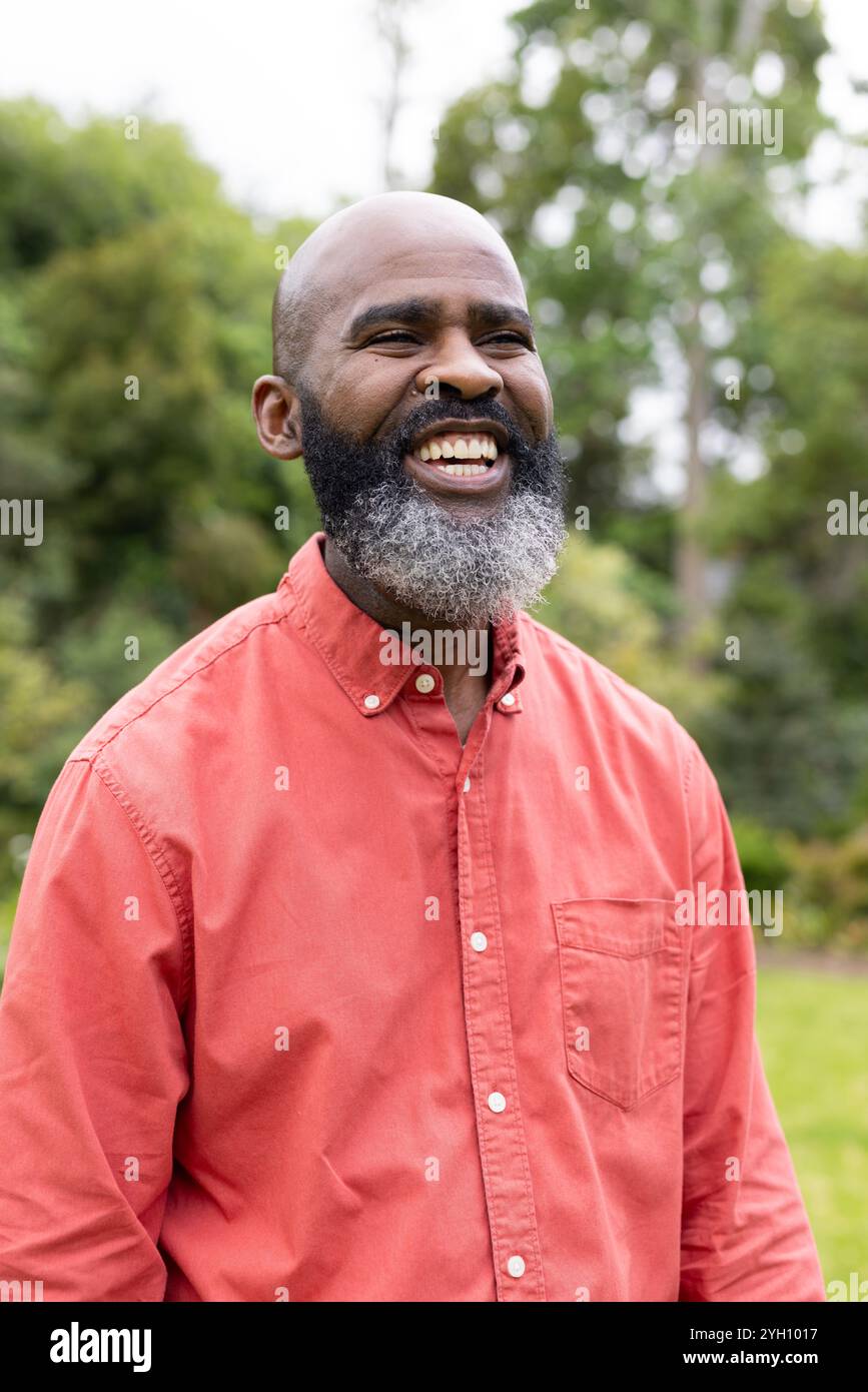 Uomo sorridente in camicia rossa che si diverte al parco all'aperto nelle giornate di sole Foto Stock