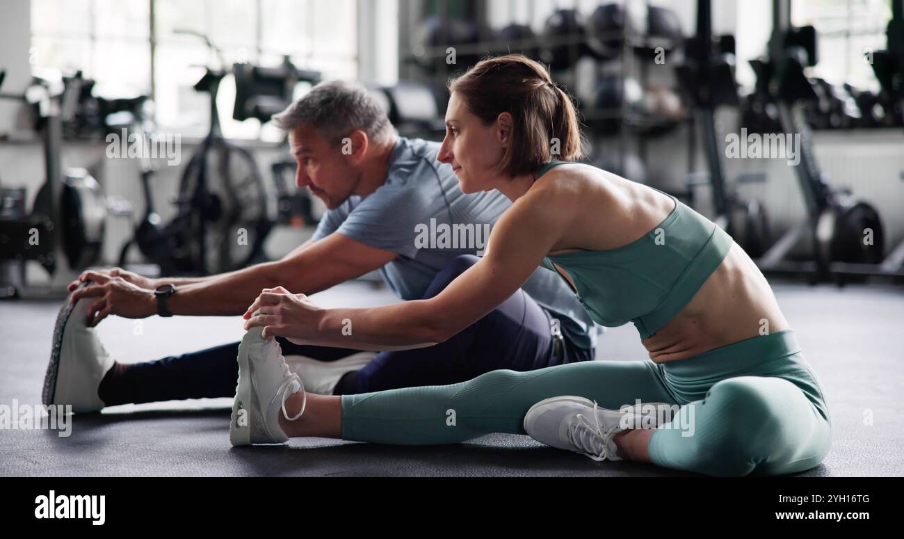 Esercizio di allungamento delle gambe in palestra. Coppia che fa sport Foto Stock