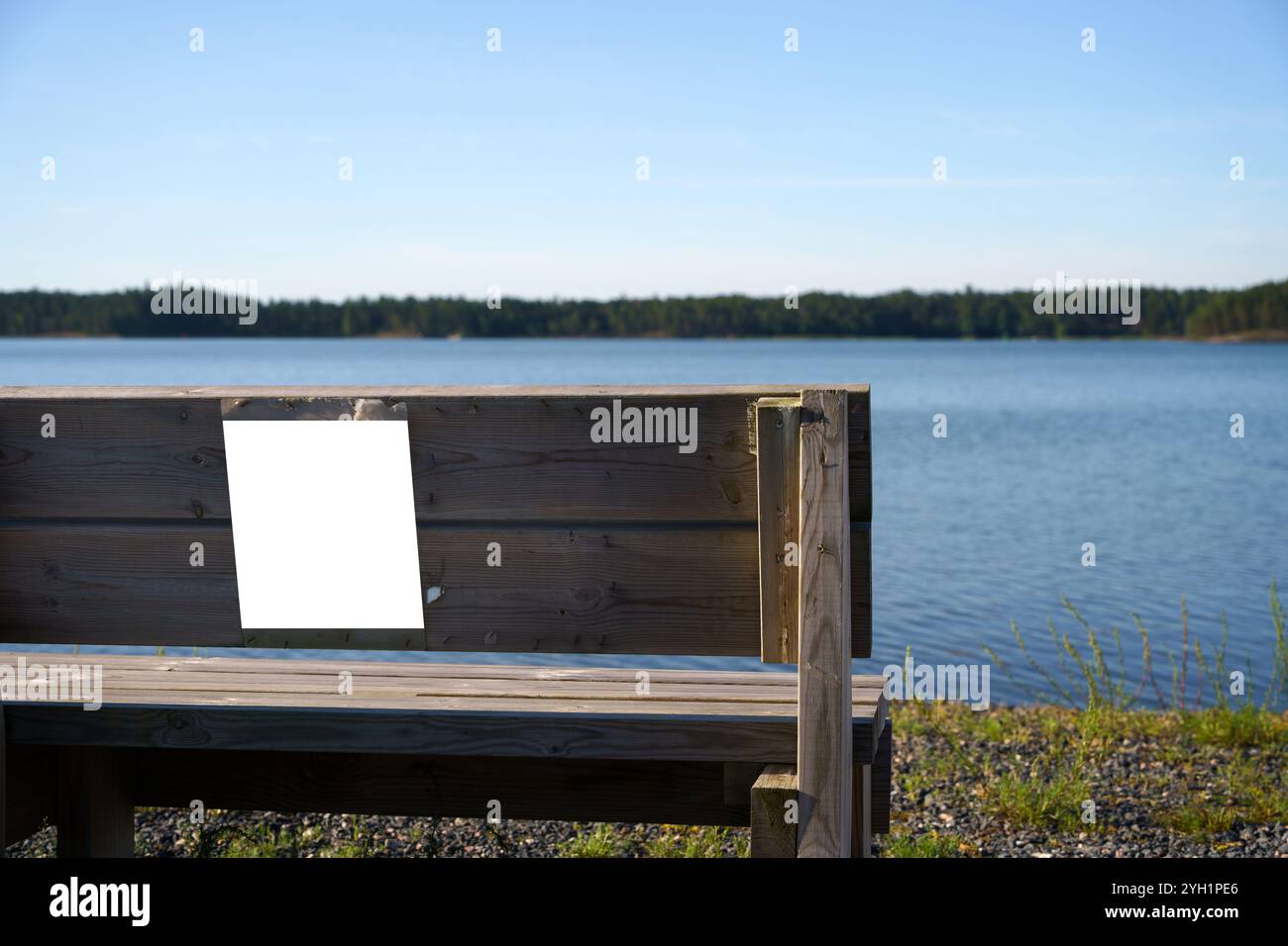 Cartello vuoto attaccato sul retro di una panchina di legno vicino al lago Foto Stock