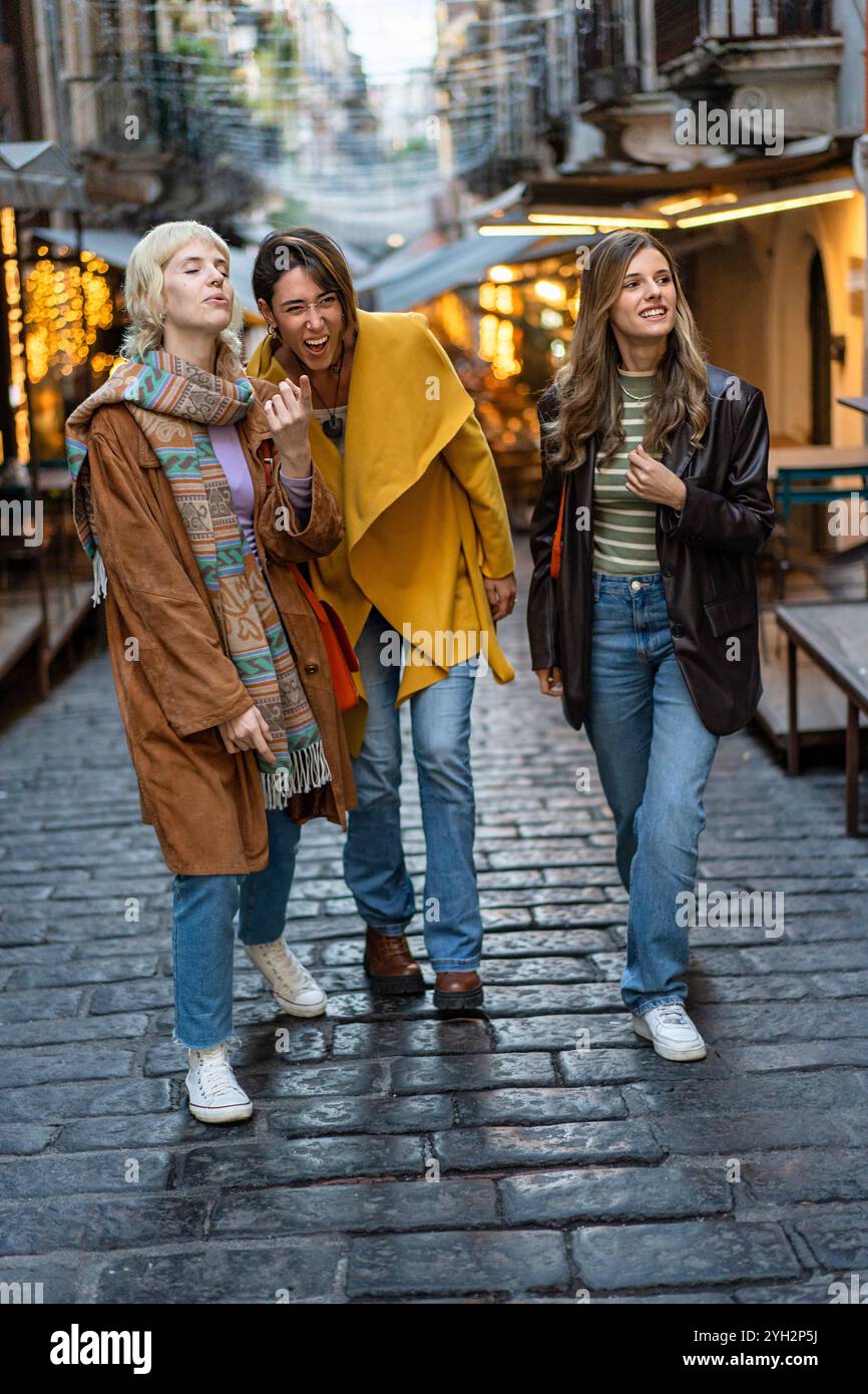 Tre amici alla moda che amano fare shopping invernale nella città europea, indossando abiti casual alla moda e cappotti stagionali Foto Stock