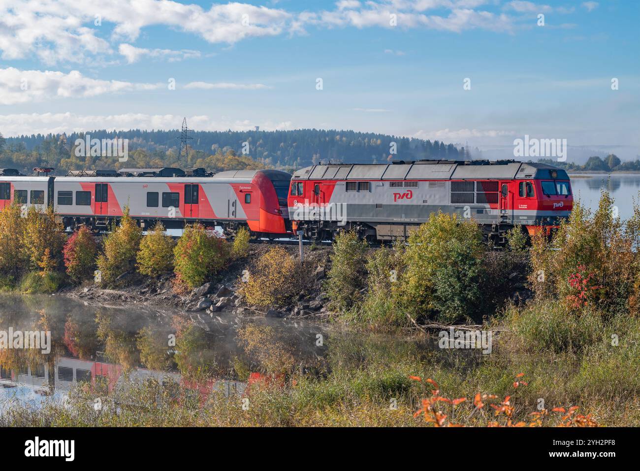 SORTAVALA, RUSSIA - 01 OTTOBRE 2024: Locomotiva diesel TEP70BS con treno elettrico ES2GP "Lastochka" su una sezione non elettrificata della ferrovia su A. Foto Stock