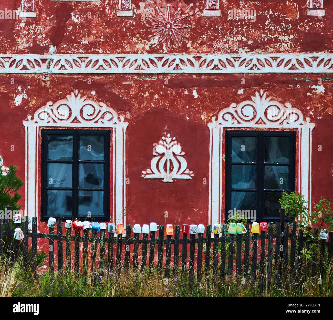 Arte murale sul davanti di una casa con una collezione di tazze sulla recinzione di picchetto in legno. Foto Stock