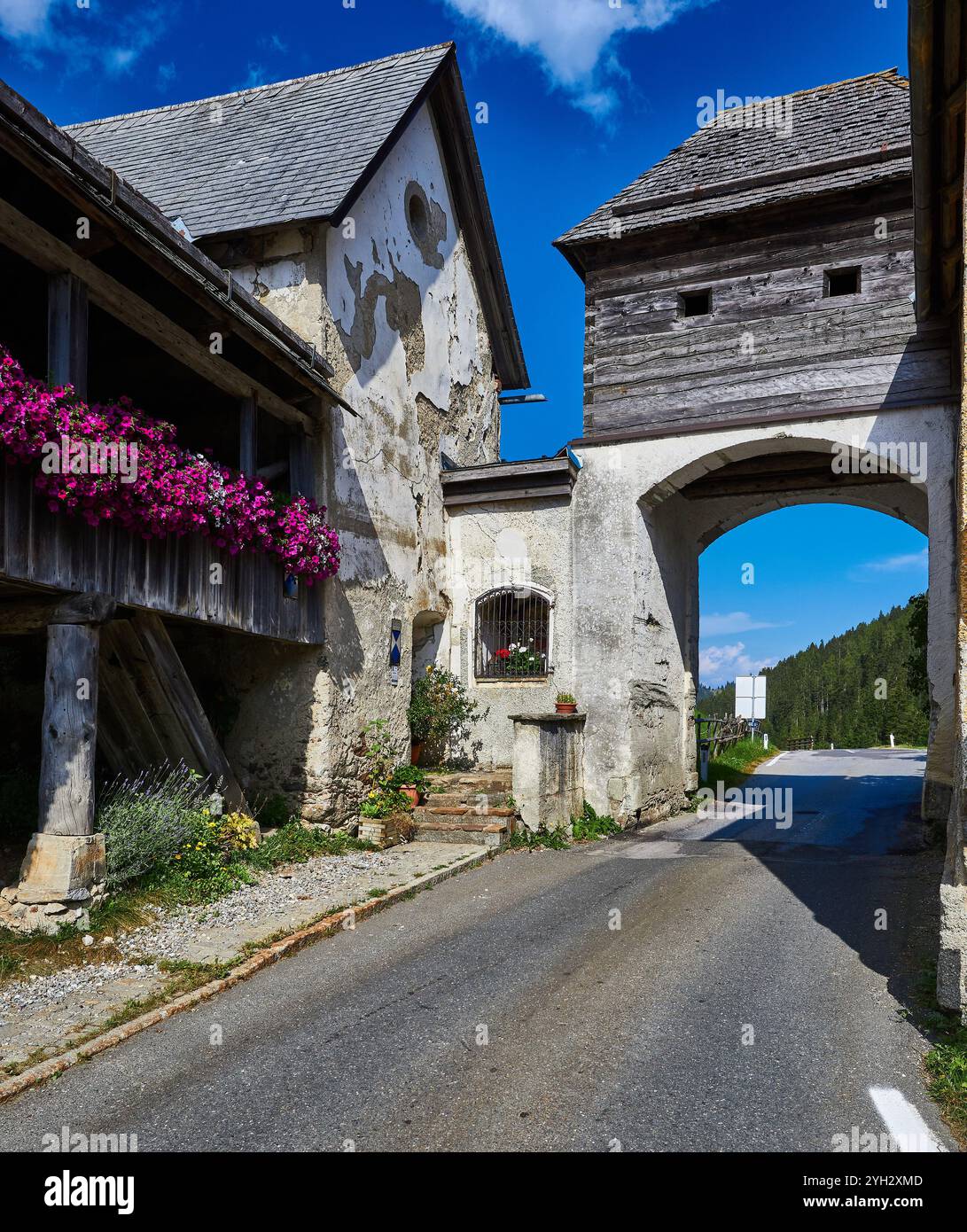 Affascinante strada storica del villaggio e arcata rustica sotto cieli azzurri Foto Stock