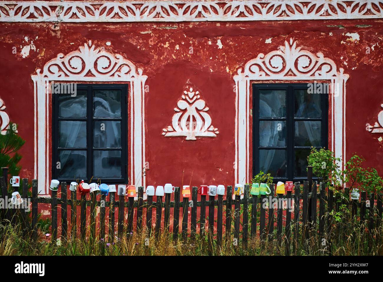 Arte murale sul davanti di una casa con una collezione di tazze sulla recinzione di picchetto in legno. Foto Stock