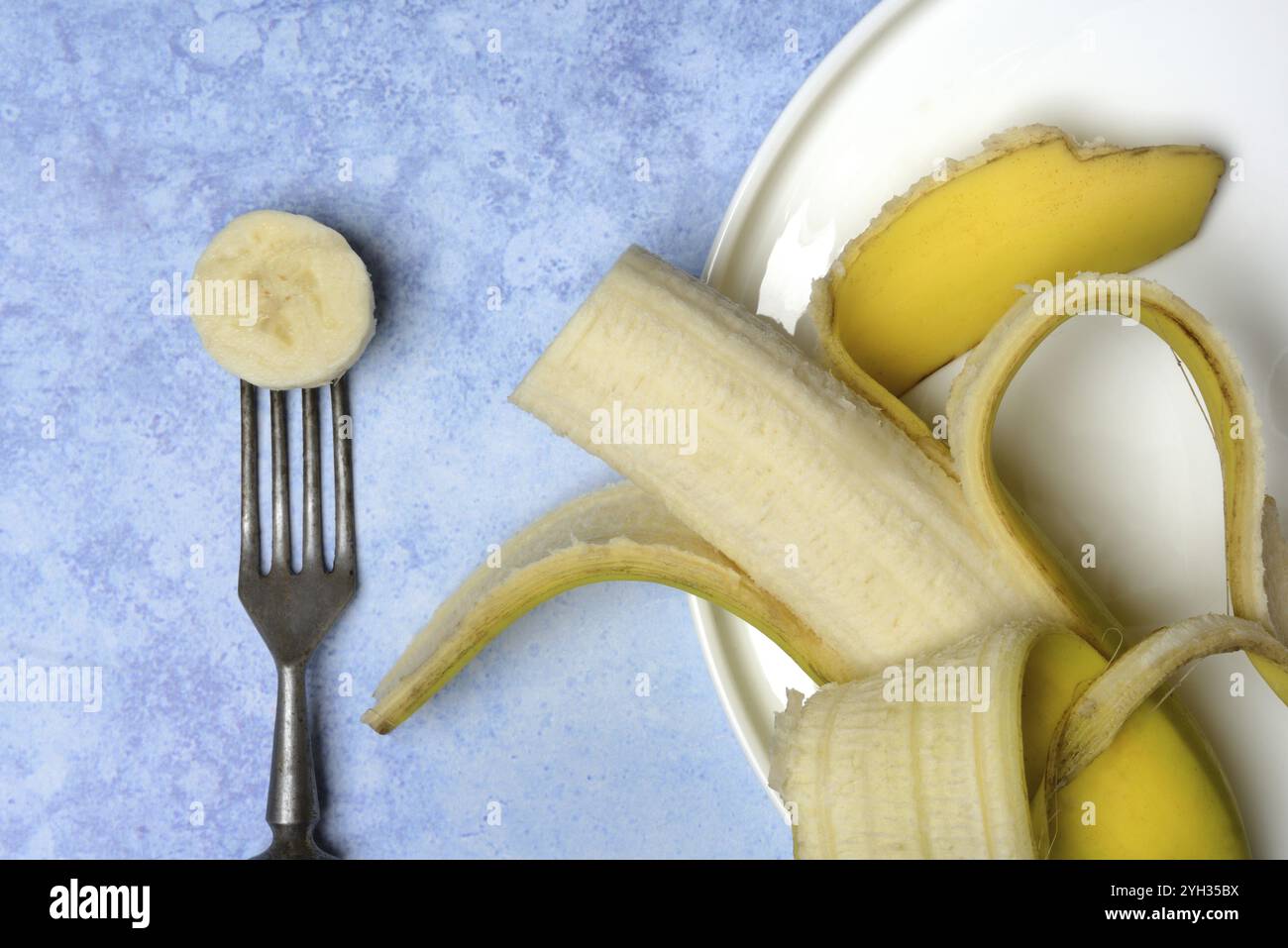 Aprire la banana sul piatto e forchetta con la fetta di banana Foto Stock