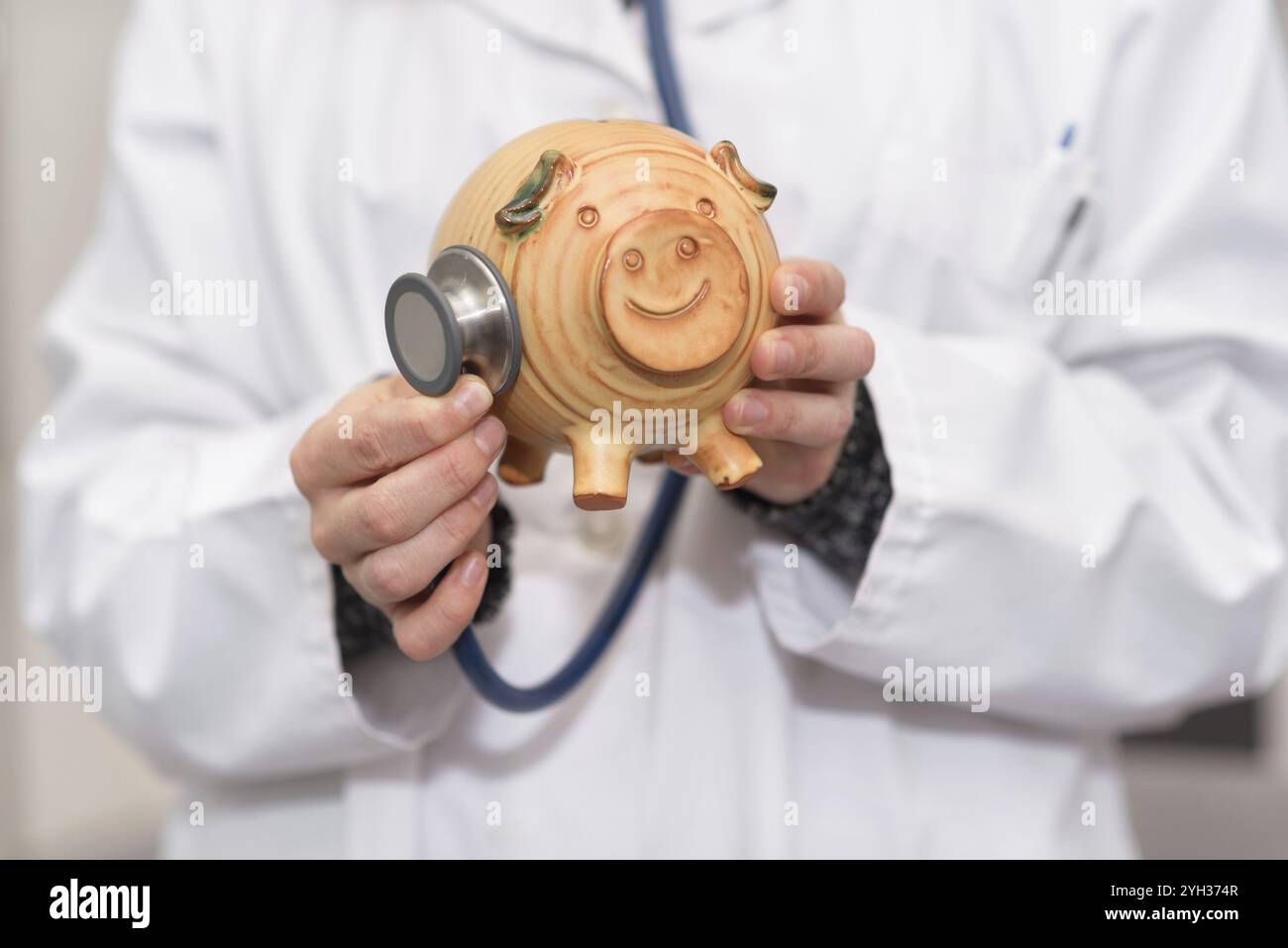 Medico che tiene il salvadanaio da vicino. Concetto di assicurazione medica e di denaro per l'assistenza sanitaria Foto Stock