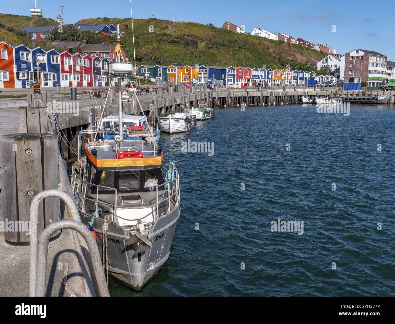 Piccole barche da pesca ormeggiate sulla riva nel porto interno e sullo sfondo case colorate protette dal patrimonio culturale, colorate baracche di aragosta Foto Stock