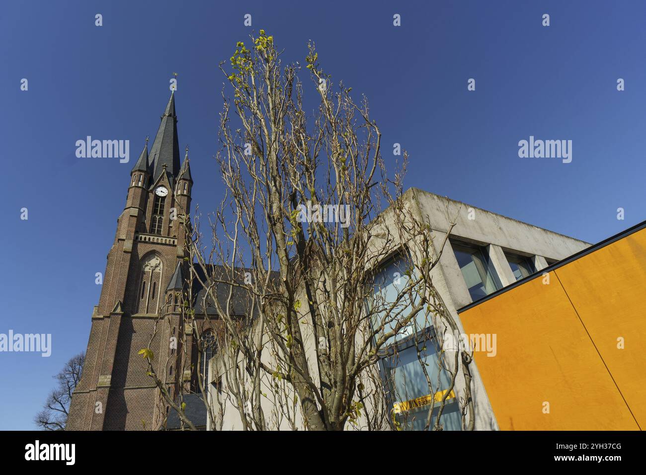 La torre della chiesa sovrasta una struttura moderna sotto un cielo limpido, Weseke, muensterland, germania Foto Stock