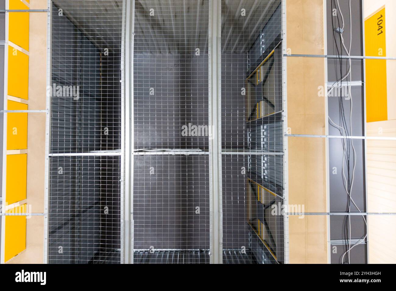 Vista dall'alto delle unità di stoccaggio in metallo organizzate con pareti a griglia e marcatori gialli in una struttura. Foto Stock
