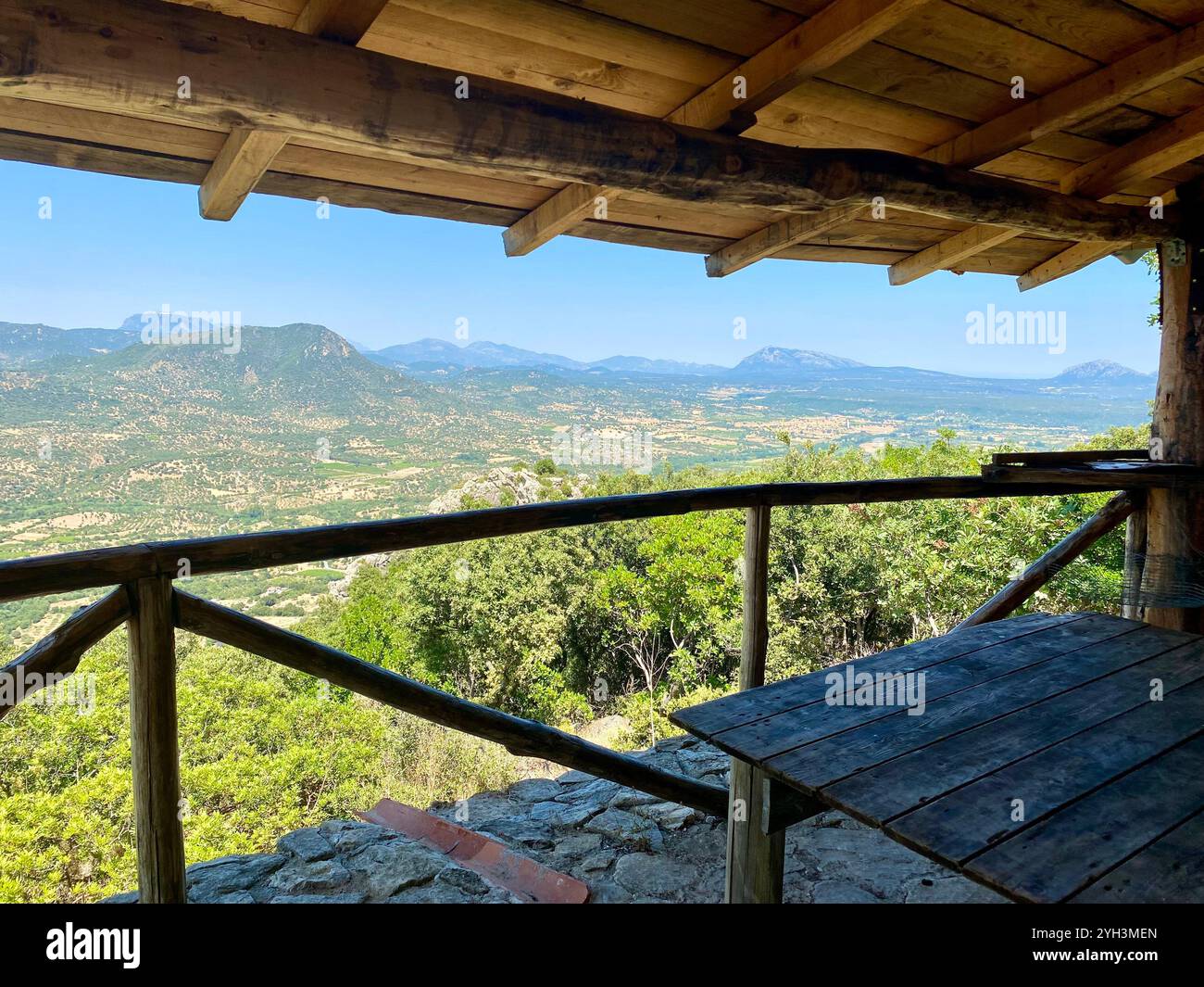 Palo di avvistamento rustico in legno con fuoco selvatico che offre vedute panoramiche delle montagne - Immagine stock catturata con smartphone