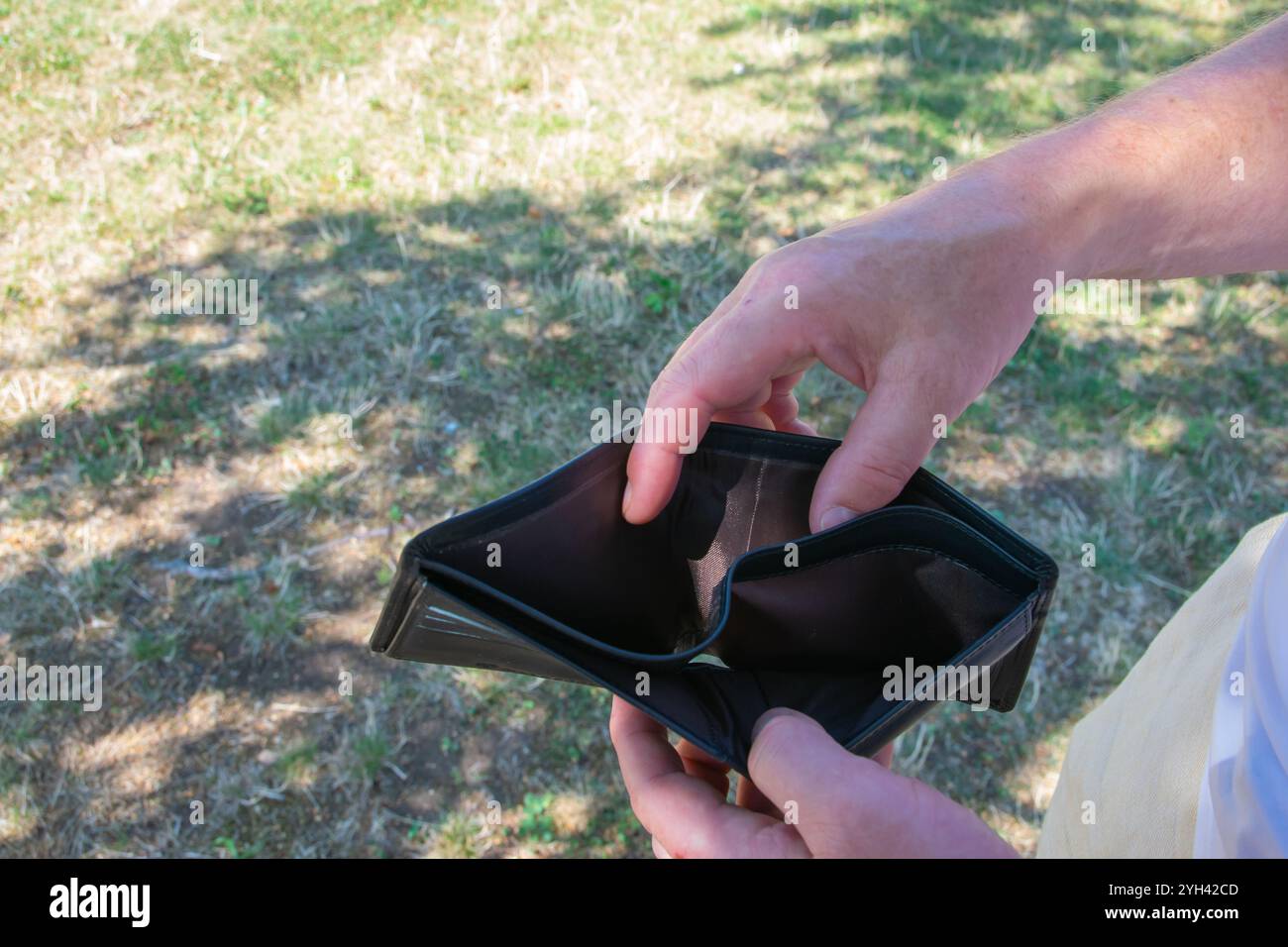 Uomo che tiene in mano il leader nero vuoto partmone. Il portafoglio senza per il concetto di commercio. Foto Stock