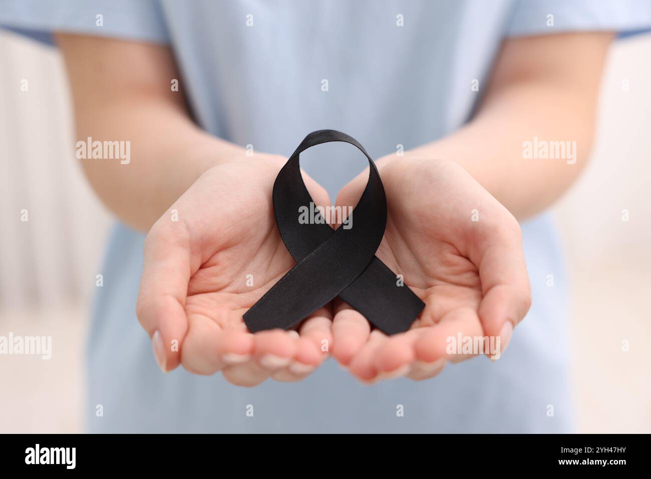 Donna con nastro nero su sfondo chiaro, primo piano. Concetto di melanoma e lutto Foto Stock