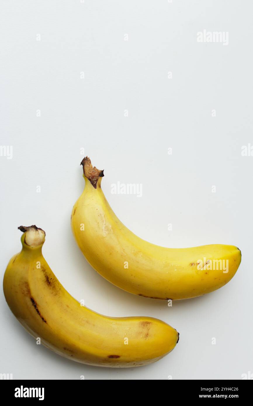 Due banane su sfondo bianco con spazio di copia. Ingrediente sano, organico, ricco di vitamina per i pasti dieta vegani. Frutta tropicale dolce e nutriente. Foto Stock