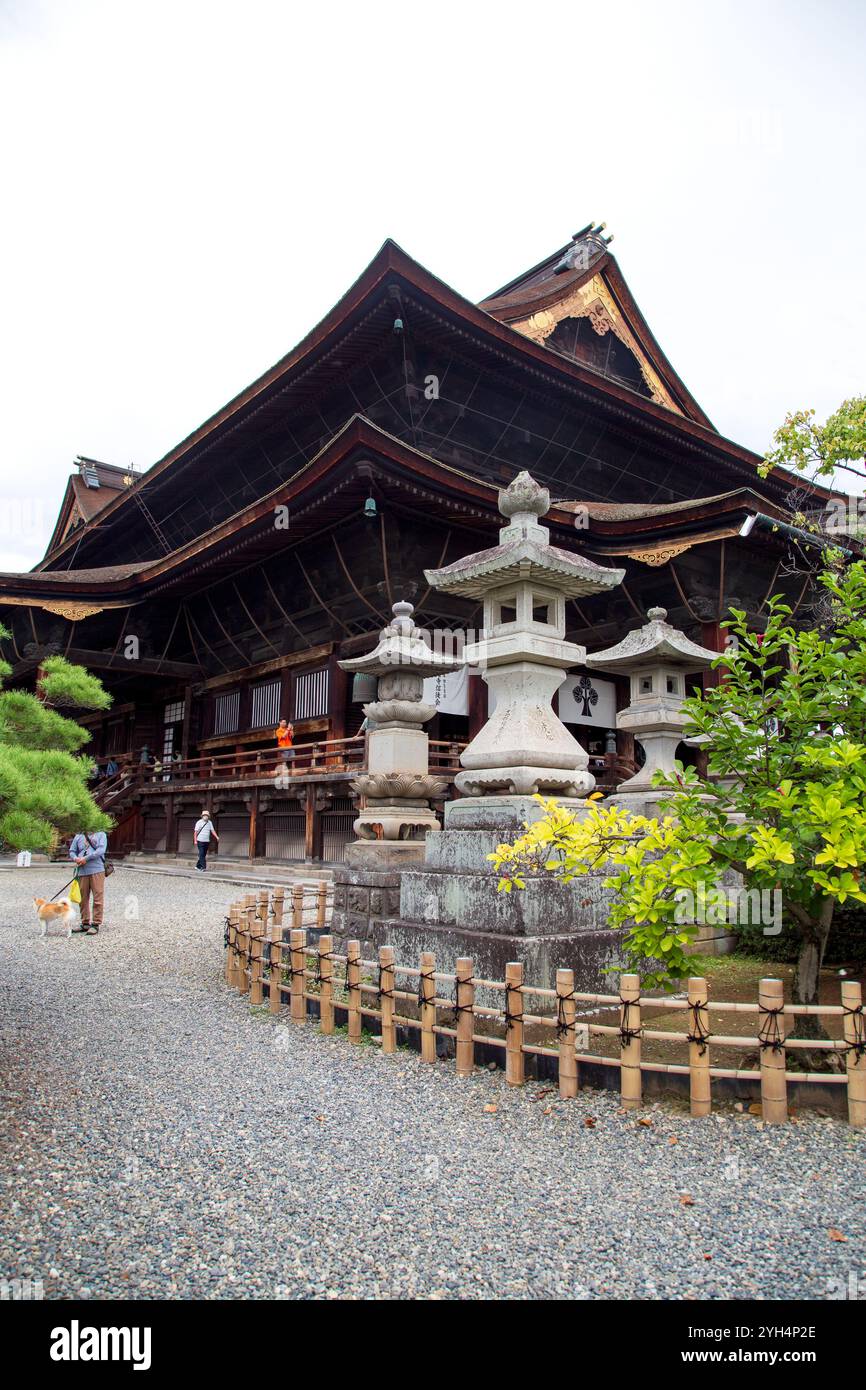 La sala principale del tempio Zenkoji a Nagano con lanterne in pietra di fronte. Foto Stock
