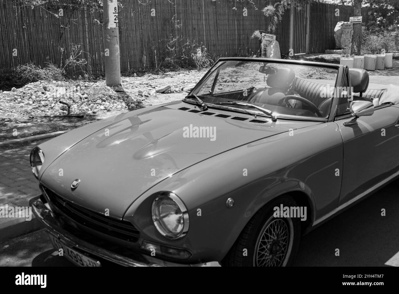 Mitzpe Ramon, Israele - 10 maggio 2024: Fiat 124 Sport Spider auto da collezione d'antiquariato decappottabile parcheggiata sulla strada laterale in bianco e nero Foto Stock