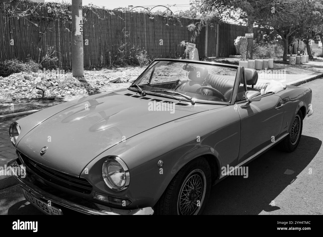 Mitzpe Ramon, Israele - 10 maggio 2024: Fiat 124 Sport Spider auto da collezione d'antiquariato decappottabile parcheggiata sulla strada laterale in bianco e nero Foto Stock