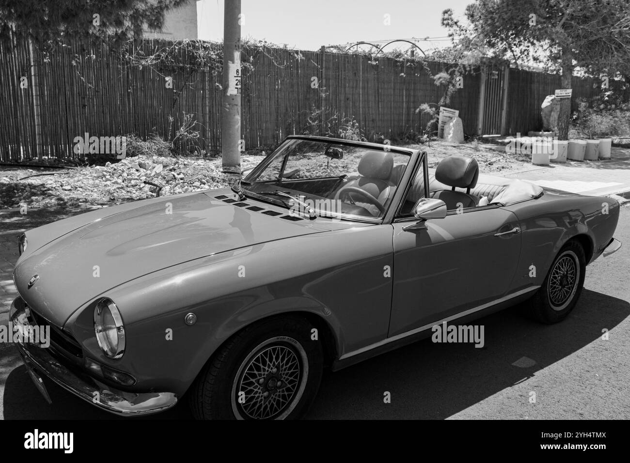 Mitzpe Ramon, Israele - 10 maggio 2024: Fiat 124 Sport Spider auto da collezione d'antiquariato decappottabile parcheggiata sulla strada laterale in bianco e nero Foto Stock