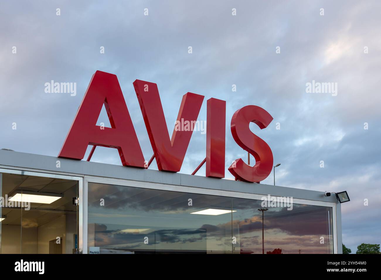 Primo piano del logo AVIS sull'edificio visto presso l'ufficio di noleggio auto in un aeroporto la mattina presto. Foto Stock