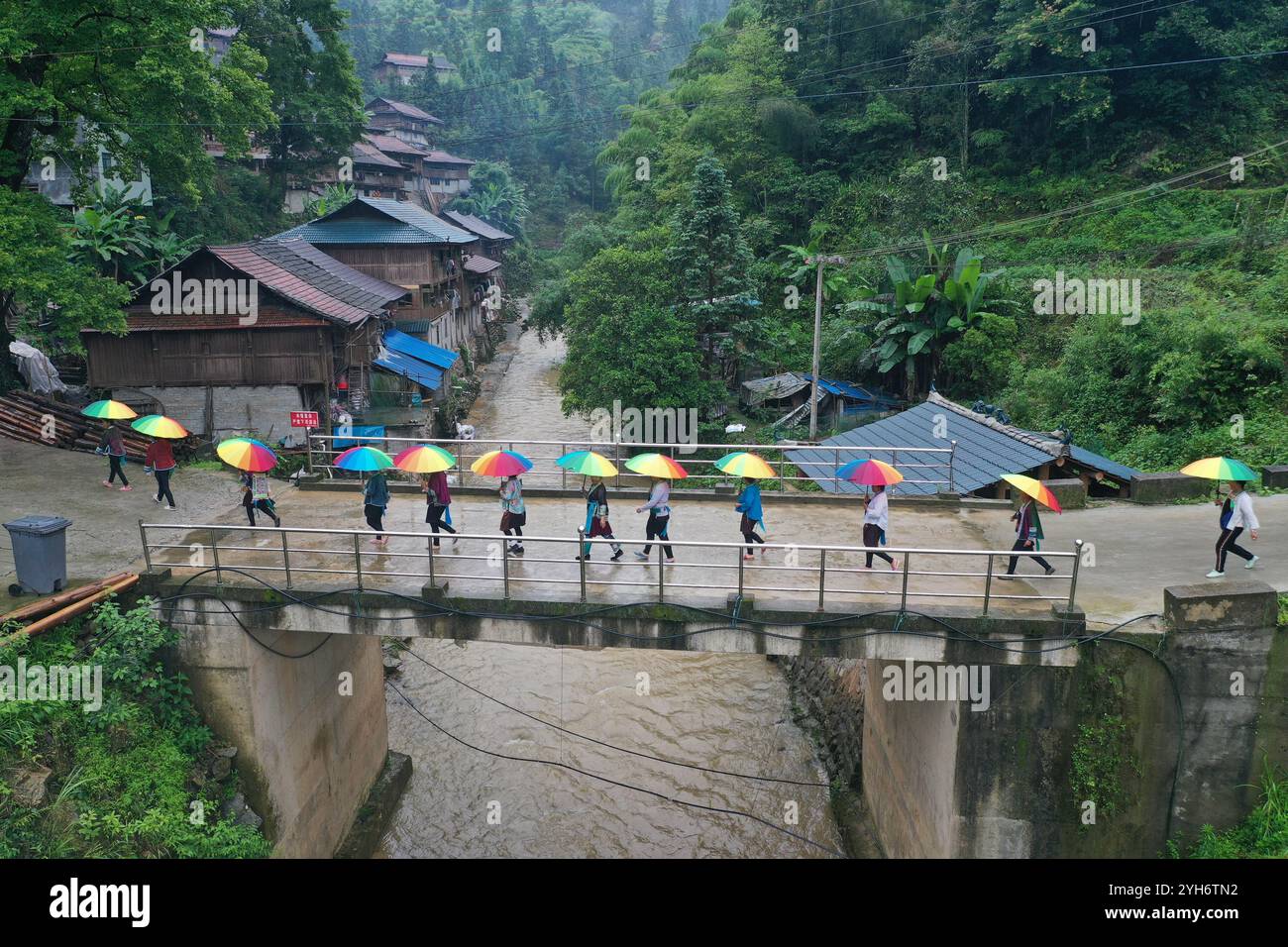 (241110) -- LIUZHOU, 10 novembre 2024 (Xinhua) -- questa foto scattata il 3 giugno 2020 mostra le donne che tornano dopo un programma di addestramento al mandarino sotto la pioggia al villaggio di Wuying al confine tra la regione autonoma Guangxi Zhuang della Cina meridionale e la provincia di Guizhou della Cina sud-occidentale. Wuying Village è un villaggio etnico-minoritario di Miao che si accosta perfettamente tra le torreggianti montagne che si estendono oltre il confine tra Guangxi e Guizhou. In passato, le montagne impraticabili e il paesaggio aspro rendevano la gente del posto estremamente povera. Grazie al sostegno degli sforzi delle autorità competenti, Wuying di recente Foto Stock