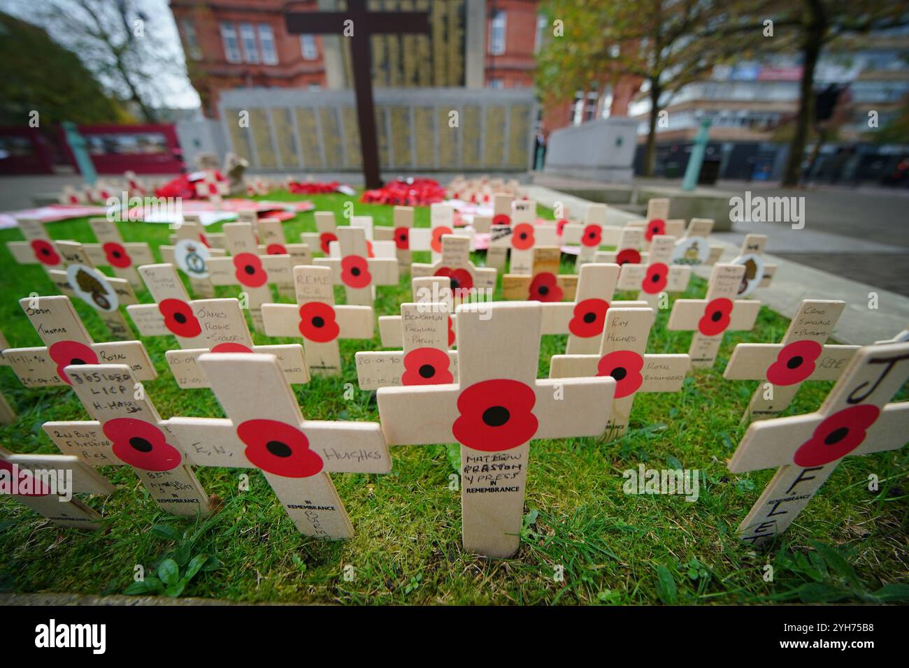 Croci di legno con papaveri e nomi di coloro che vengono ricordati prima di una ricorrenza domenicale al cenotafio in Victoria Square, St Helens, Merseyside. Data foto: Domenica 10 novembre 2024. Foto Stock